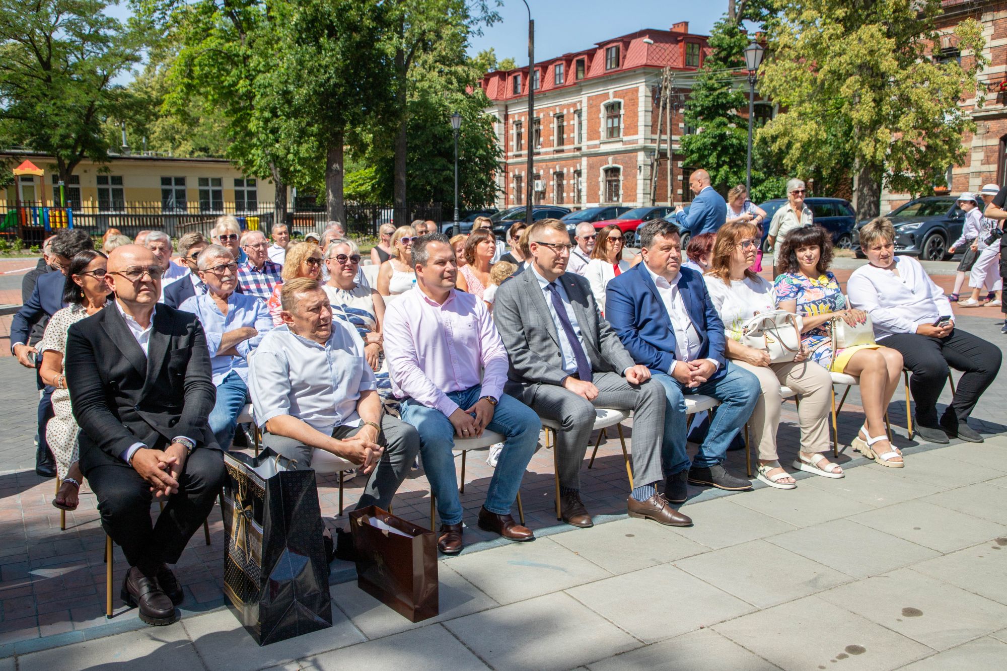 Zdjęcie grupowe zaproszonych gości, którzy siedzą na krzesłach.